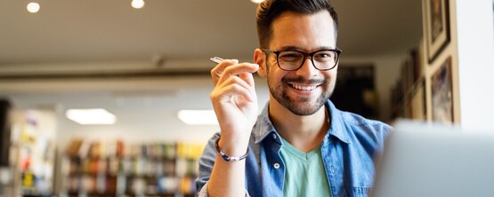 smiling-male-student-working-studying-library-liggend.jpg